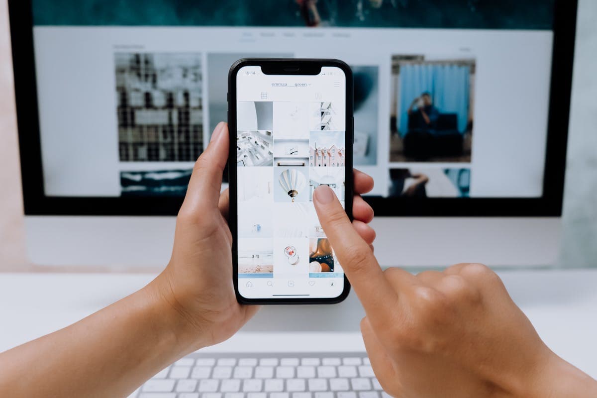 Person browsing streaming apps on a phone in front of a laptop