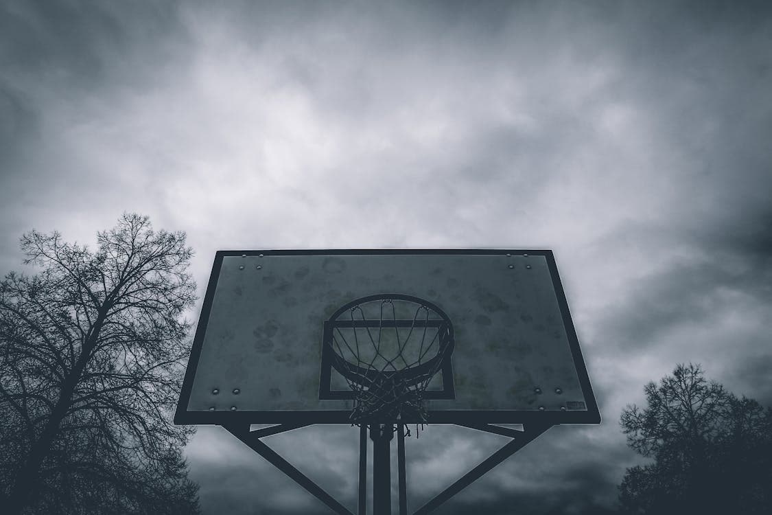 Outdoor basketball hoop under a stormy sky
