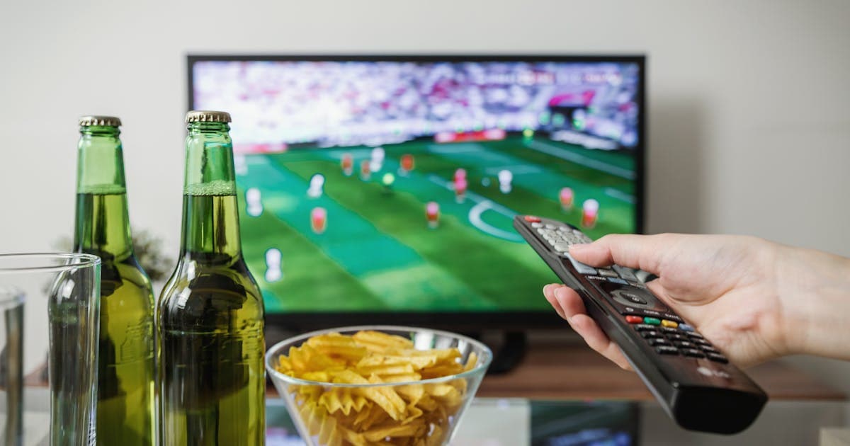 Live game on a TV with a remote and snacks on the table